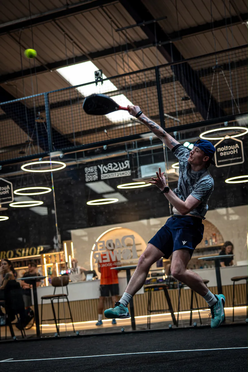A coach stretching for a forehand on the indoor courts