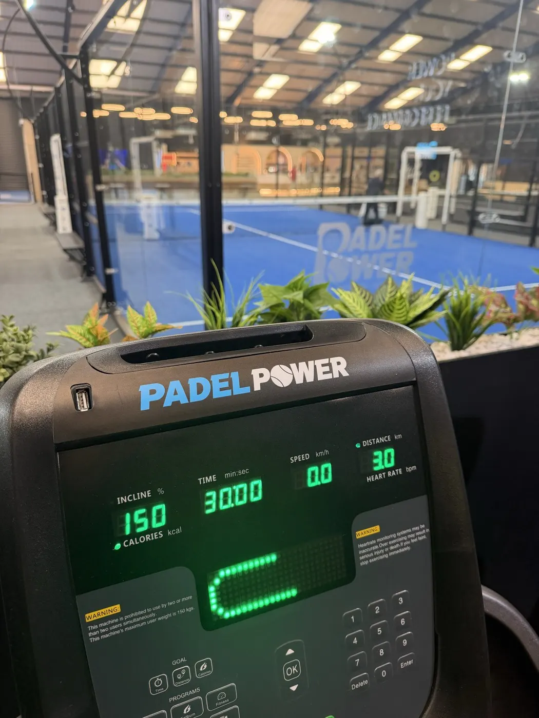 Cardio machine console with the padel courts behind