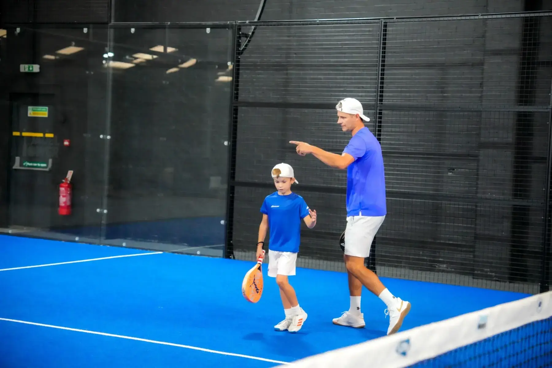 A coach guiding a junior player on court