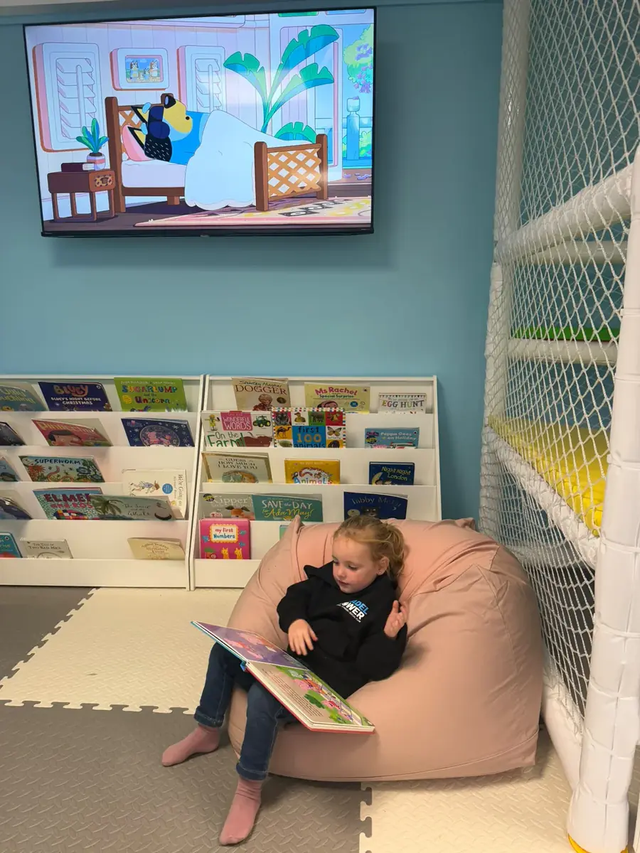 A child reading in the Kids Zone book corner